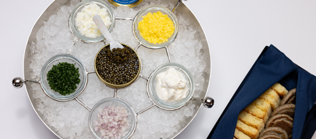 6 jars of caviars arranged over ice in a bowl with a side of toast pointes