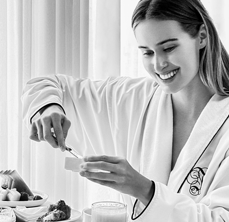 Woman scooping out of a dish with a full breakfast food filled tray