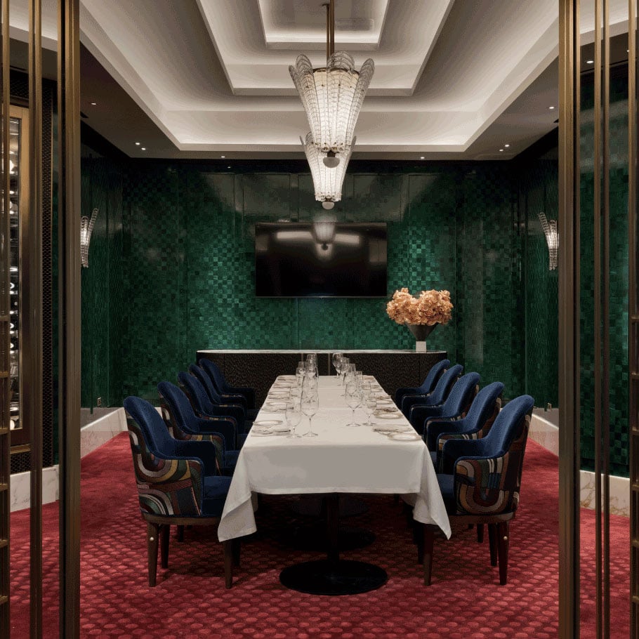 Interior long table with a white tablecloth, and blue chairs in a green dining room at Don's Prime