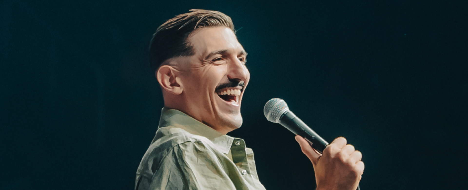Comedian Andrew Schulz holding a microphone