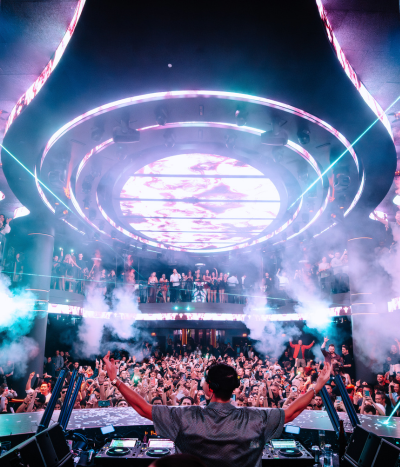 LIV Nightclub with DJ at the focal point with fog machines fogging above the crowd of people