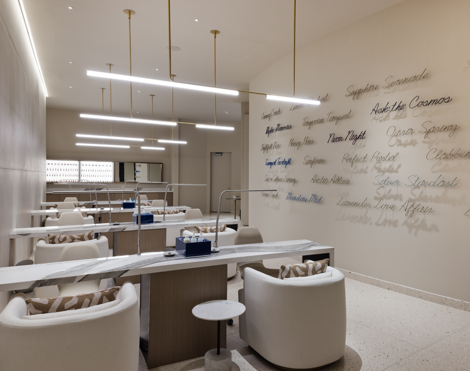 Rows of nail stations with artistic text on the wall