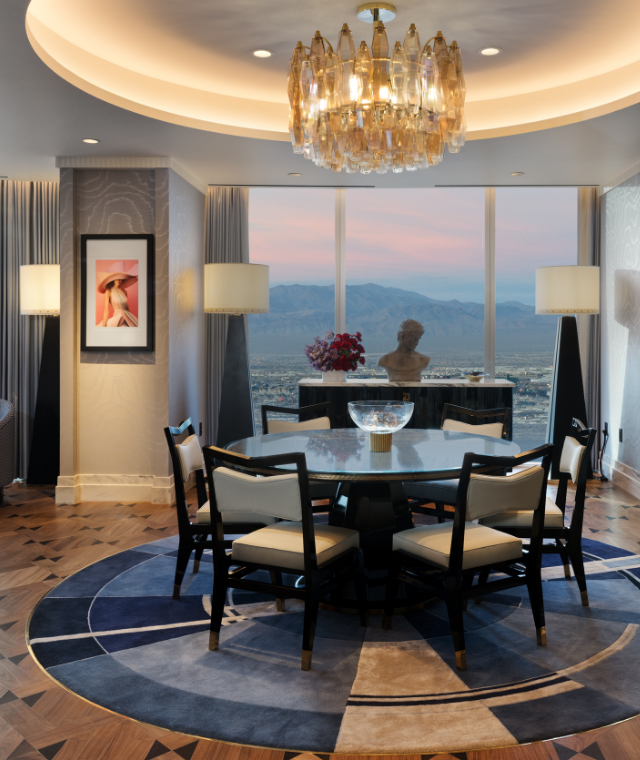 Circular table under a chandelier in front of a window with a mountain vista