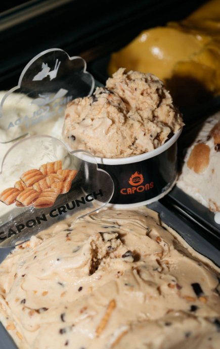Scoop of ice cream in a cup, surrounded by the serving area for other flavors of ice cream