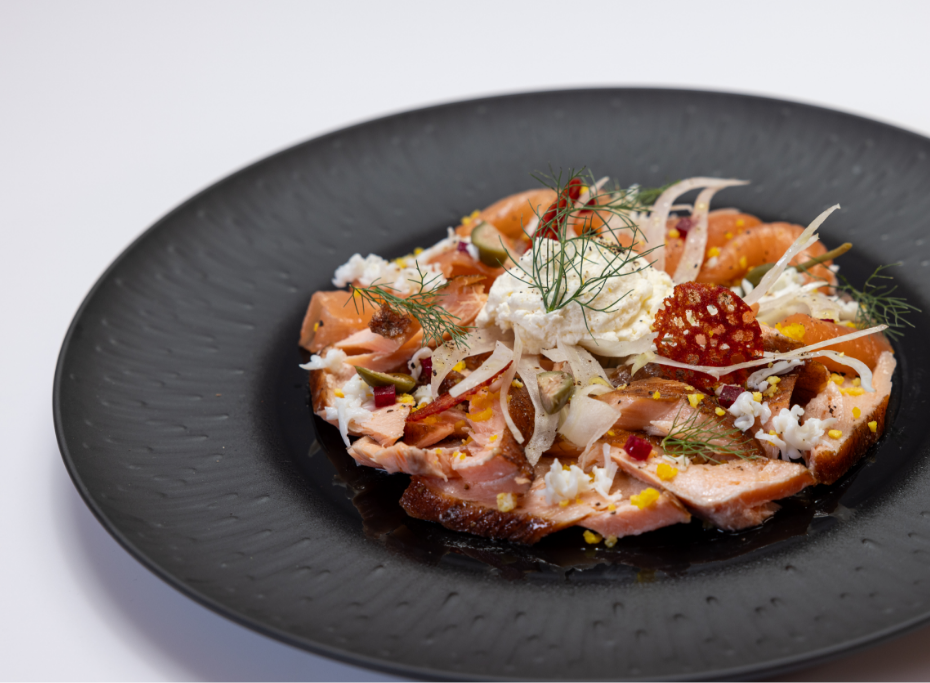 Fish and meat dish under cheese and garnishes