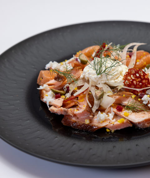 Fish and meat dish under cheese and garnishes