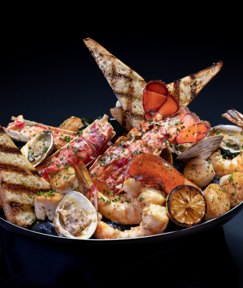 Bowl of a variety of cooked seafood and grilled bread