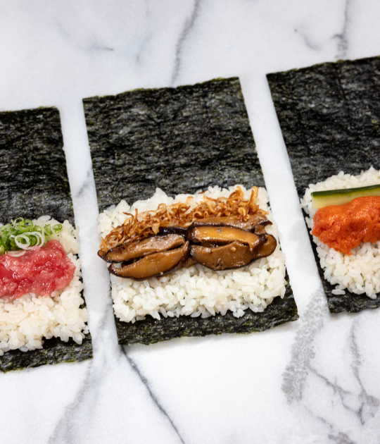 3 different pieces of sushi waiting to be finished by being wrapped in seaweed