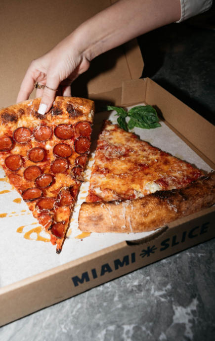 Slice of pepperoni pizza being lifted from a box with cheese slice