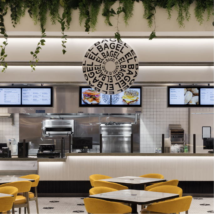 El Bagel sign logo hanging in the quick service restaurant area with seating