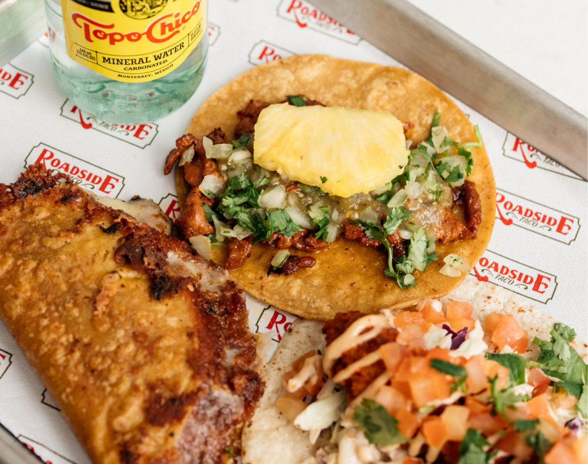 Paper lined tray with Topo-Chico mineral water and 2 open tacos and a hard taco