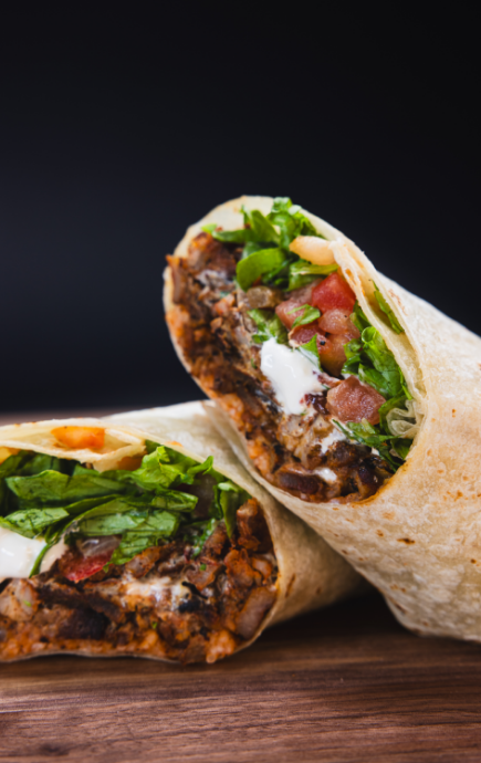 Cross section of a burrito with tomatoes, sour cream, lettuce and meat