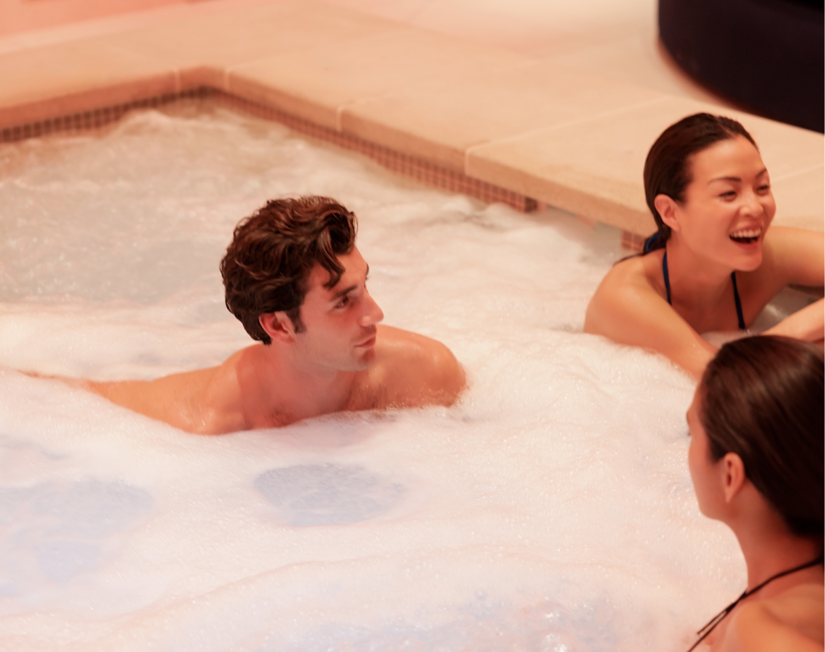 3 people sitting in a pool with bubbles