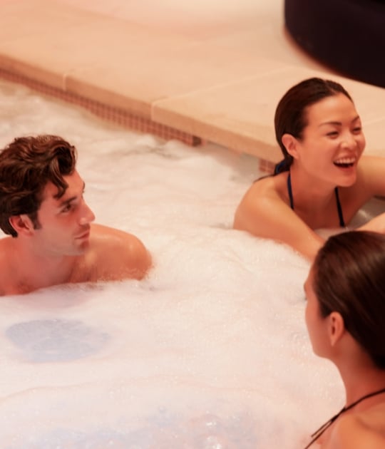 3 people sitting in a pool with bubbles