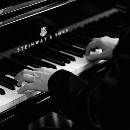 Hands playing a piano in black and white