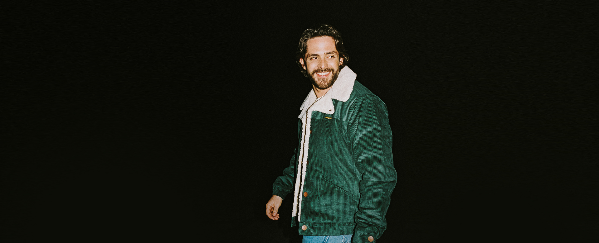 Man in green jacket on dark background