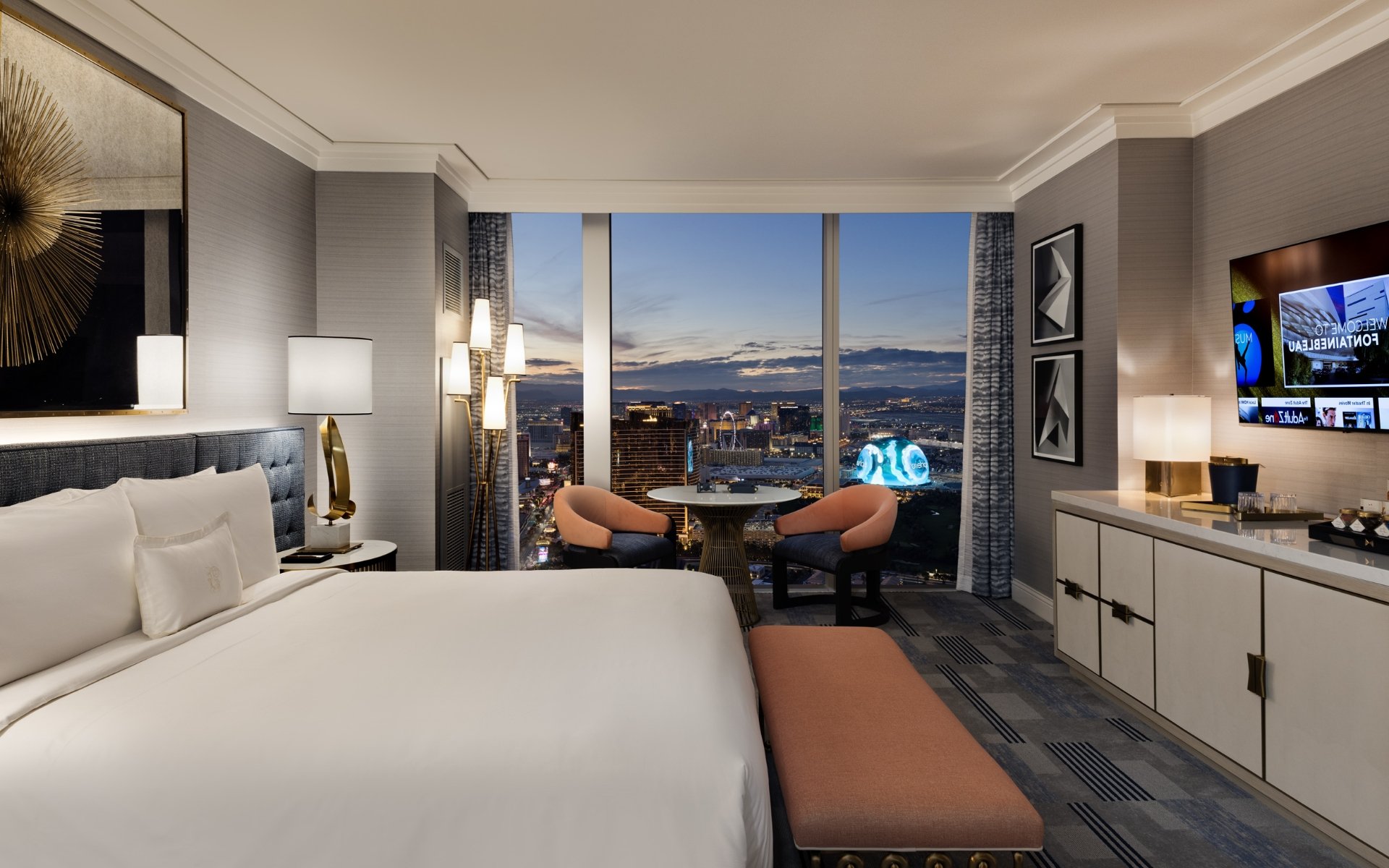 Bed by 2 nightstands with lamps underneath gold art piece