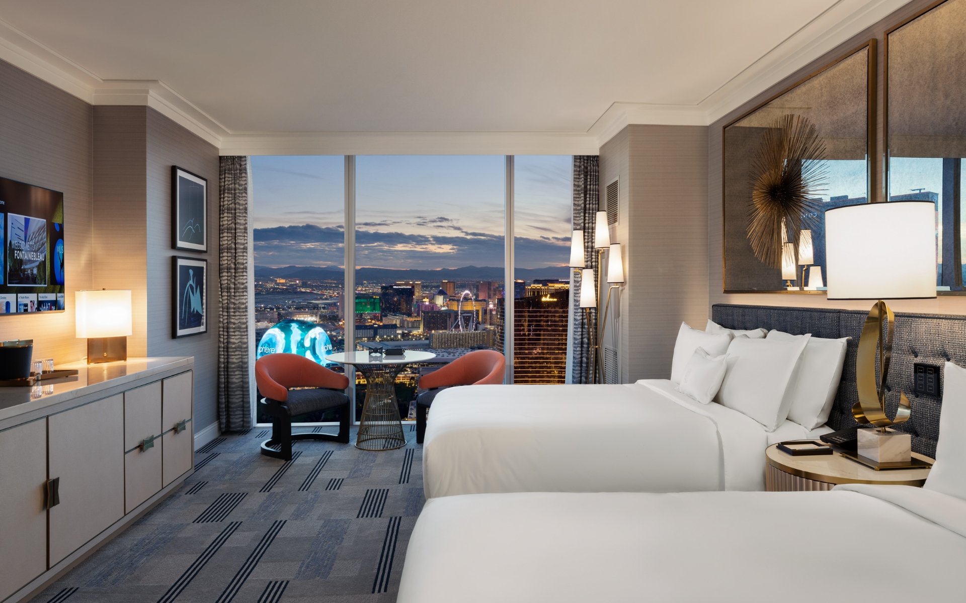 Beds by 2 nightstands with lamps underneath gold art piece