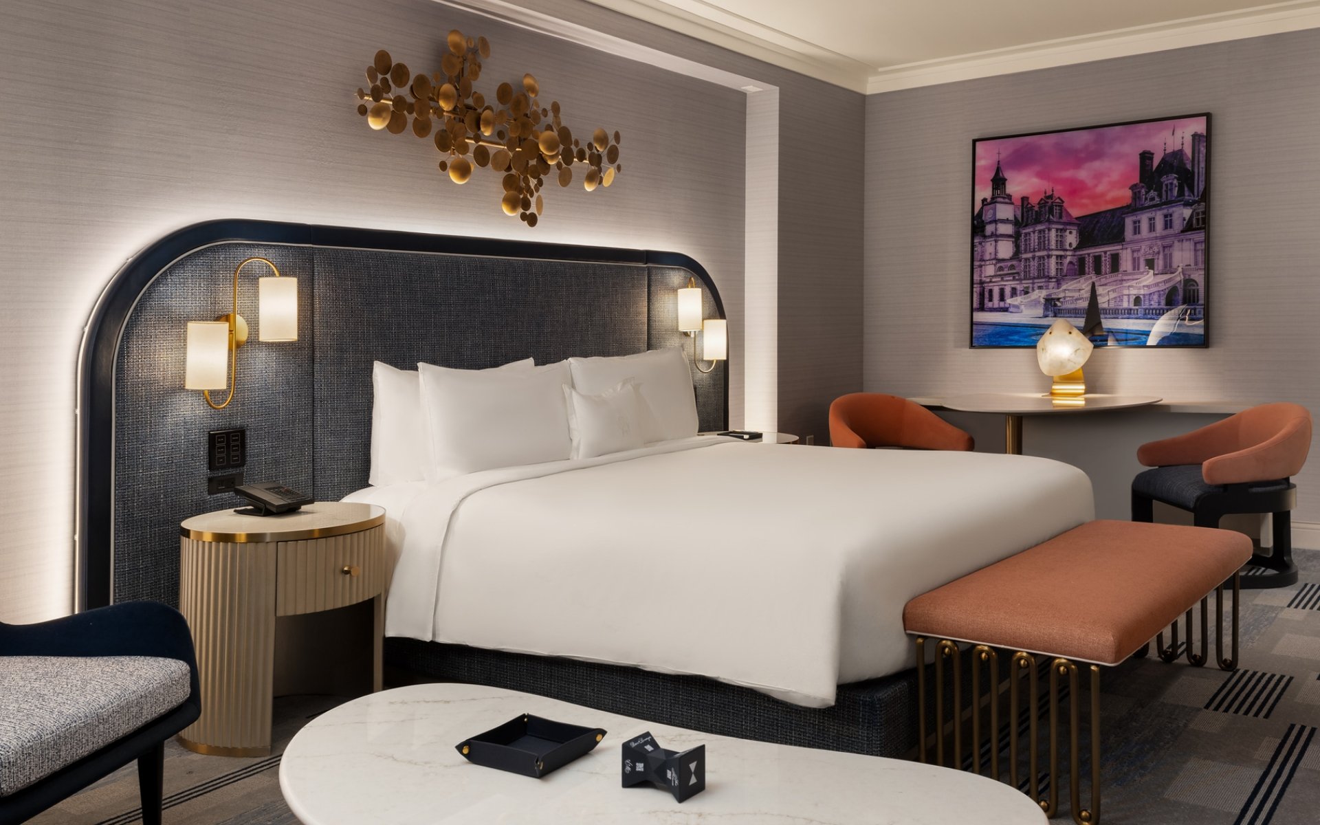 Bed framed by 2 nightstands with lamps underneath gold art piece