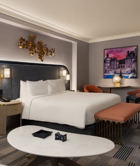 Bed framed by 2 nightstands with lamps underneath gold art piece