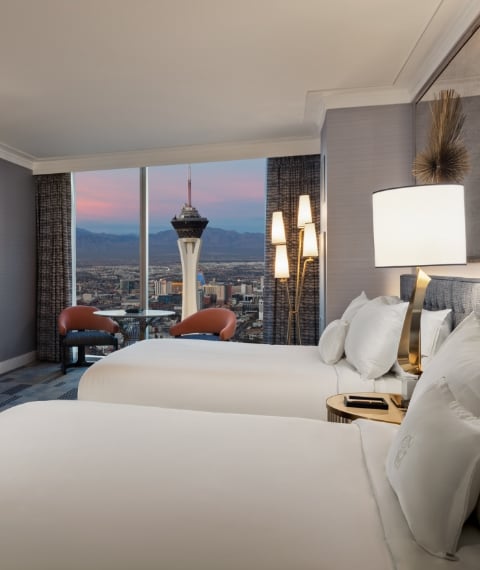 Beds by 2 nightstands with lamps underneath gold art piece