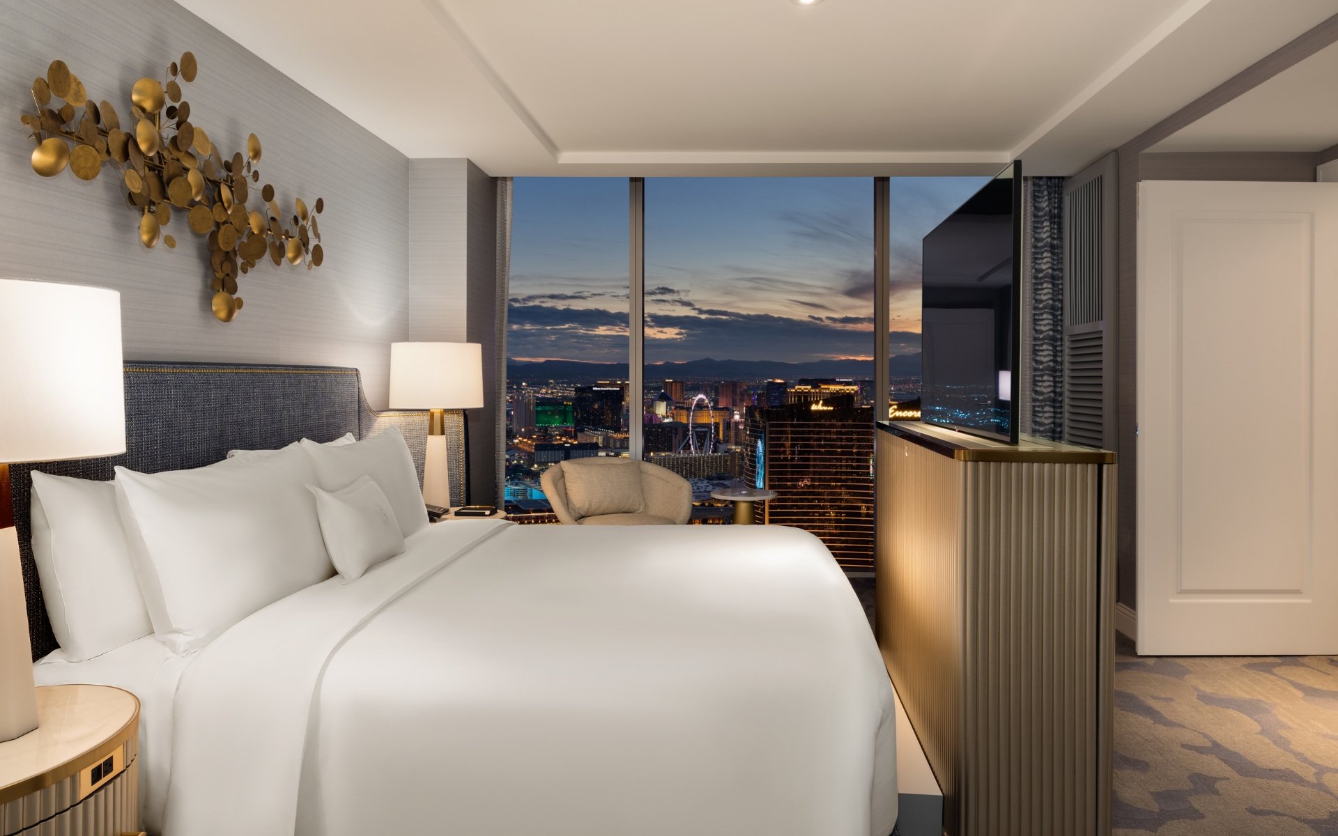 Hotel room example with bed, couch, table and art.