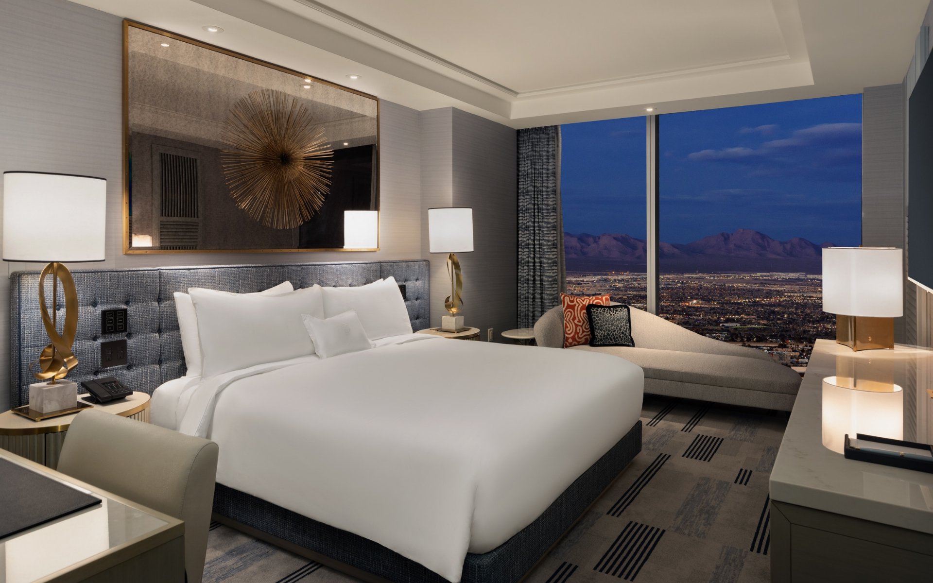 Bed framed by 2 nightstands with lamps underneath gold art piece