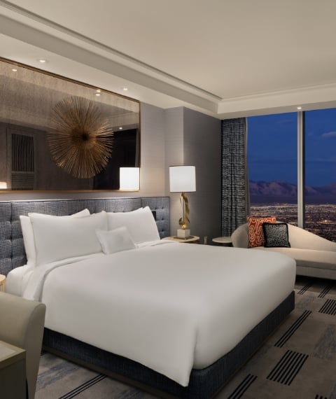 Bed framed by 2 nightstands with lamps underneath gold art piece