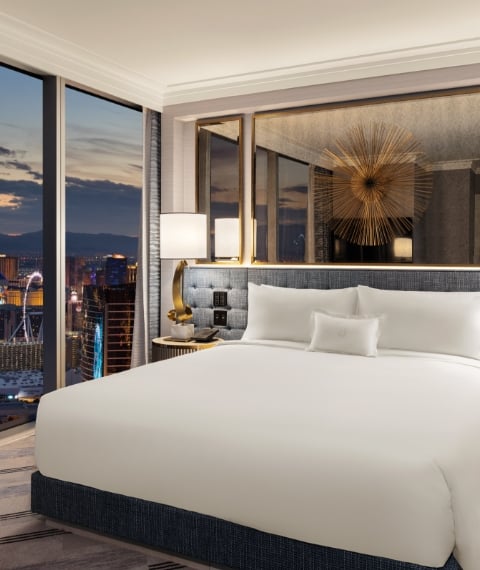 Bed framed by 2 nightstands with lamps underneath gold art piece