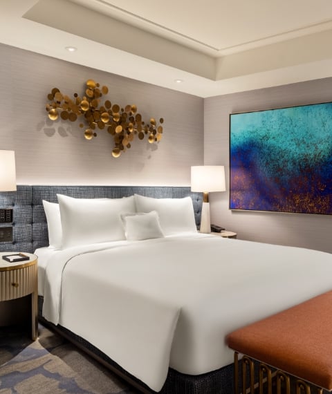 Hotel room example with bed, couch, table and art.