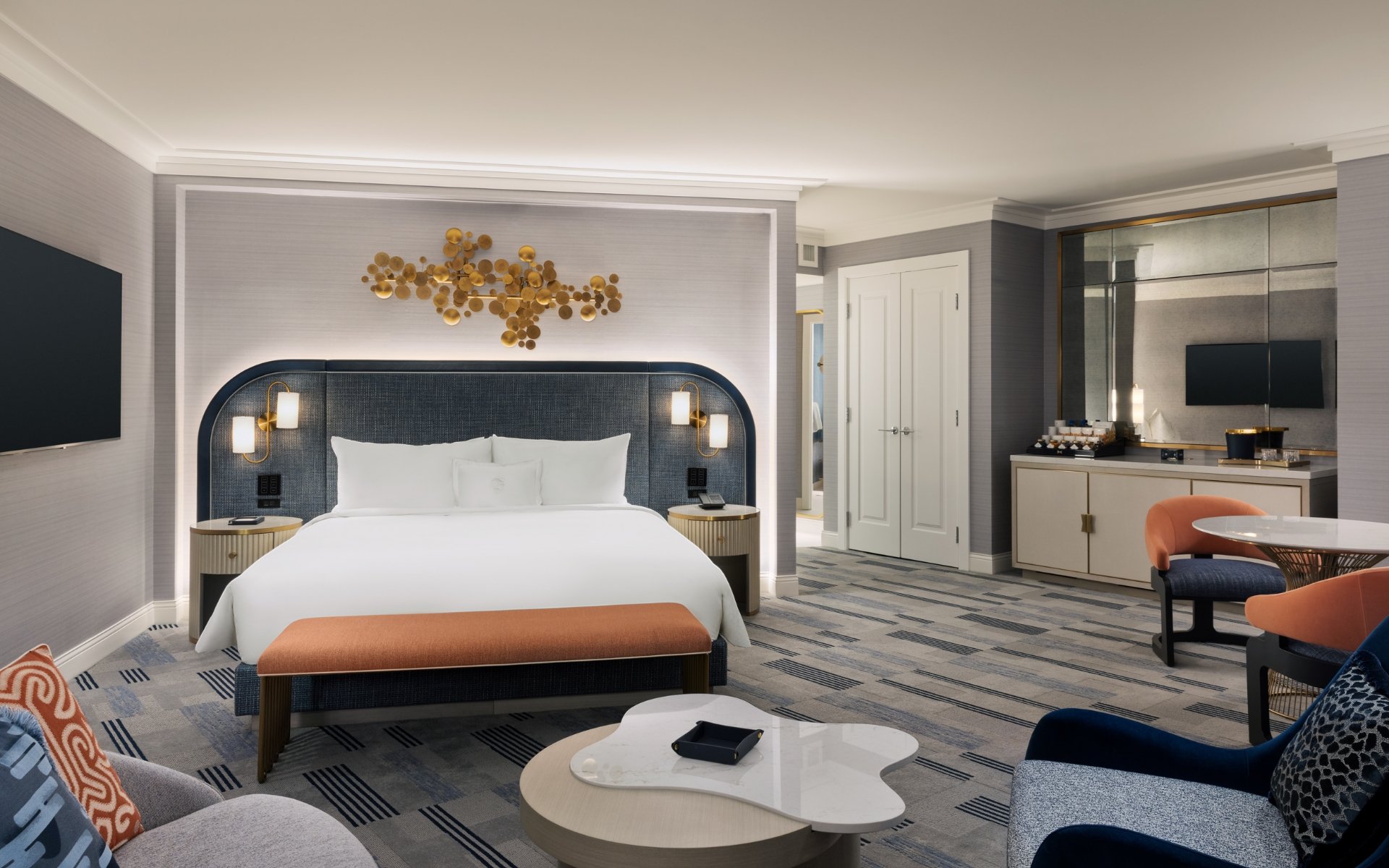 Bed framed by 2 nightstands with lamps underneath gold art piece