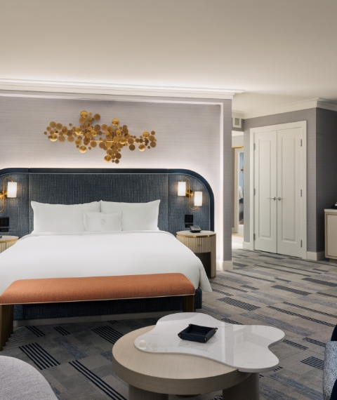 Bed framed by 2 nightstands with lamps underneath gold art piece