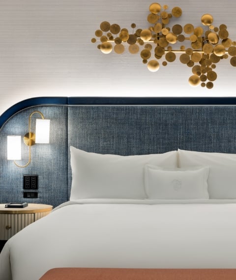 Bed framed by 2 nightstands with lamps underneath gold art piece