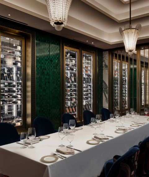 Restaurant dining space with green walls and wine fridge