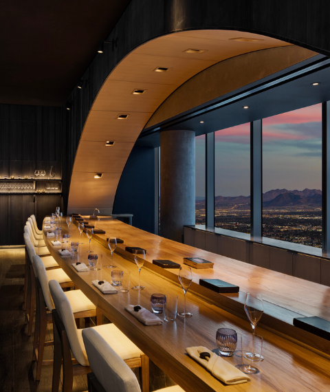 Ito dining space with beige seats underneath a wooden table, facing a window.