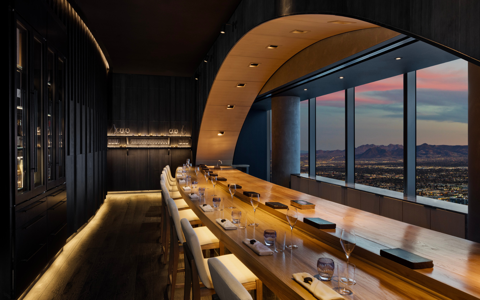 Ito dining space with beige seats underneath a wooden table, facing a window.