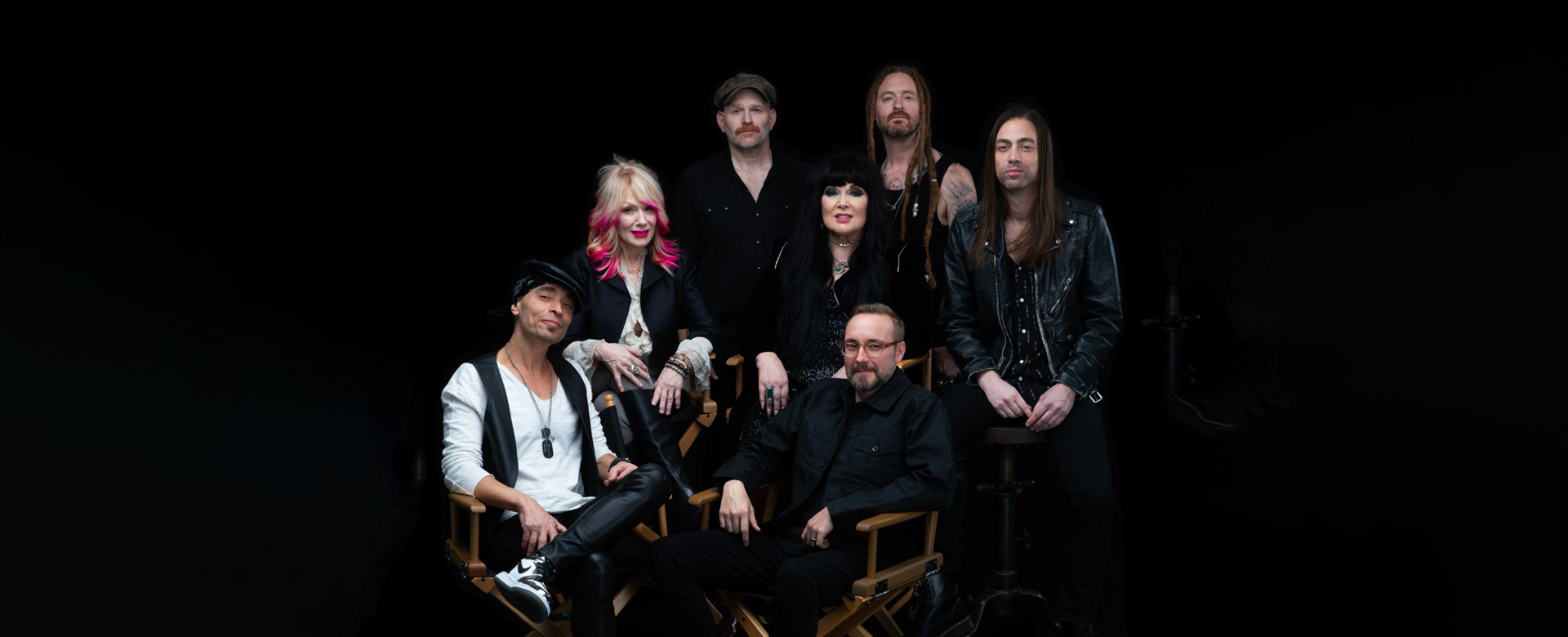 Heart band members sitting and standing against a black background
