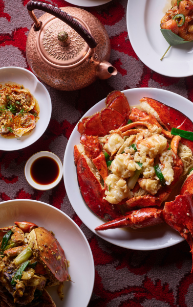 Plates of food, and teapots on a red textured surface