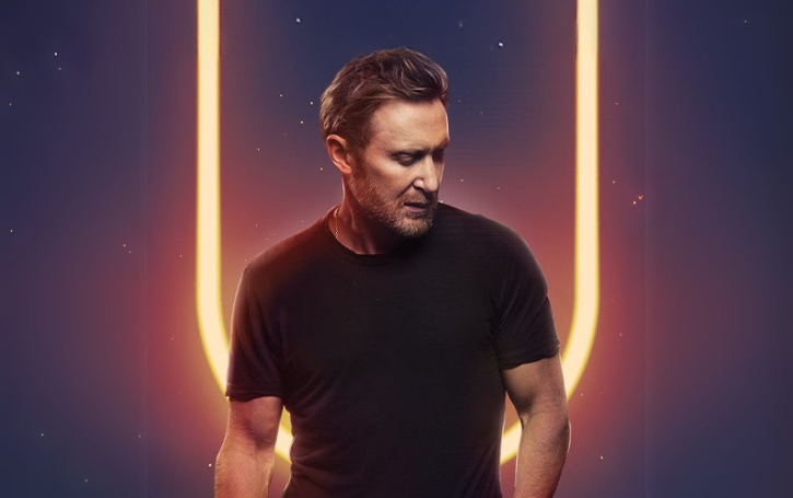 David Guetta against a dark background with yellow light.