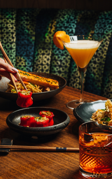 Table of food and drinks with hands holding chopsticks
