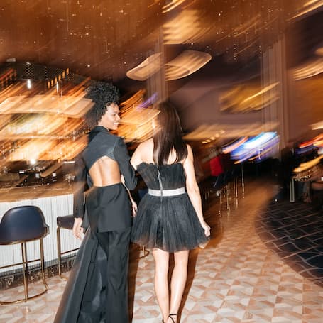 Pair of women in evening dresses walking through a deliberately blurred background