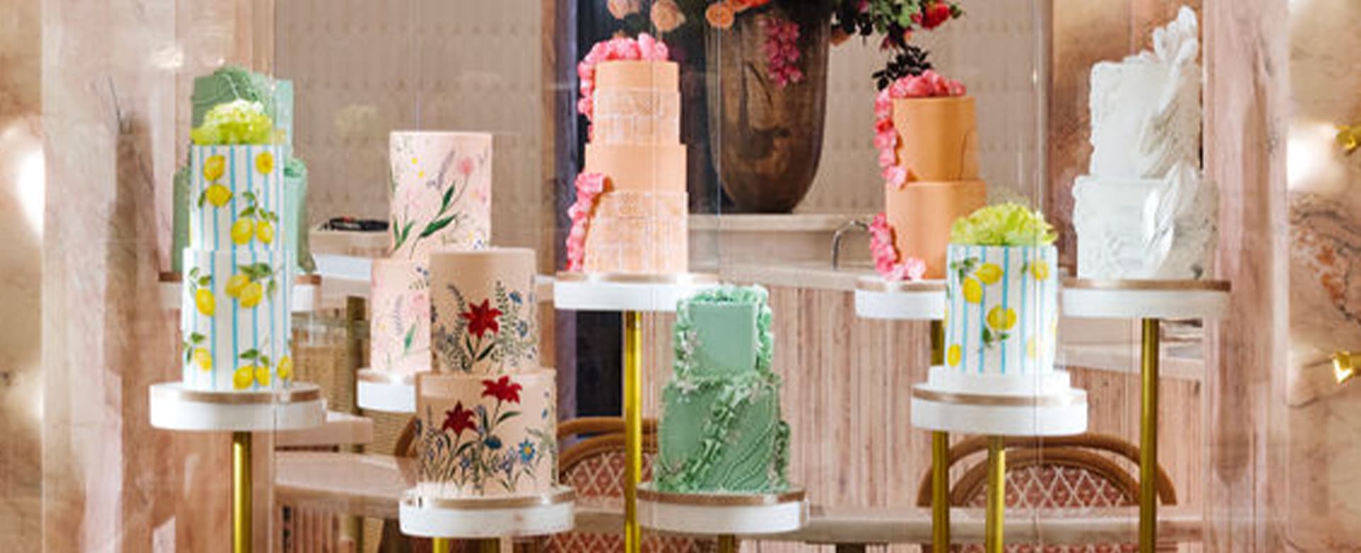 Decorated cakes on pedestals against a pink pastel background