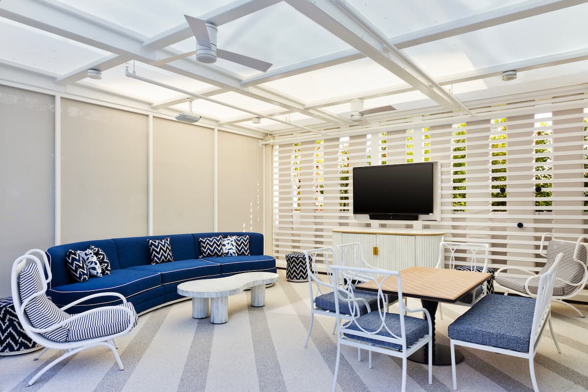 Seating area with couch, tables, chairs, fan, and TV