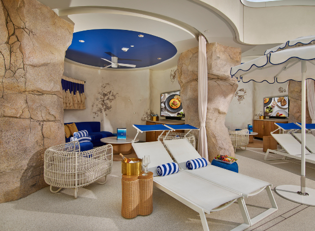 Outdoor seating area with rocky walls, couches, lounge chairs, and umbrellas