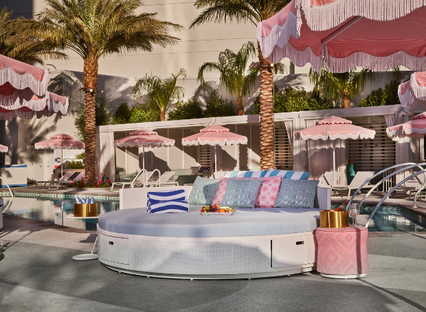Daybed with lounge chair, umbrella, towels, bottles, champagne, fruit tray and pink accents