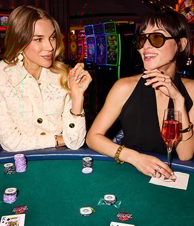 2 women sitting at a poker table with chips and drink at Fontainebleau Las Vegas