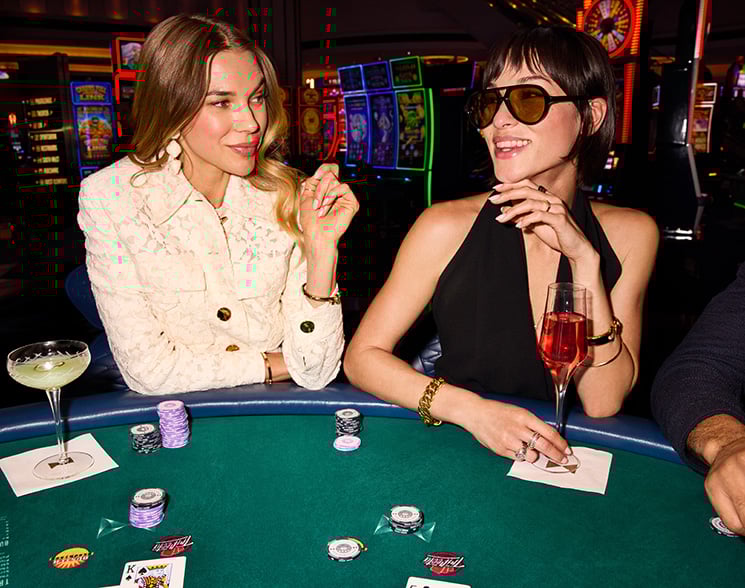 2 women sitting at a poker table with chips and drinks at Fontainebleau Las Vegas