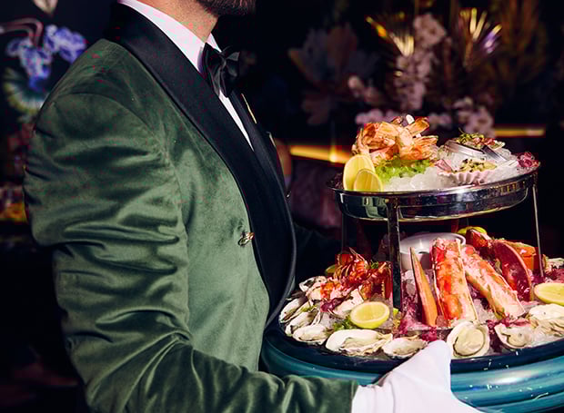 Waiter carrying tower of seafood in Papi Steak