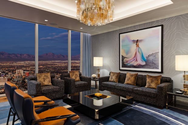 Seating area around a coffee table under art and chandelier with a view of Las Vegas from one of the rooms at Fontainebleau Las Vegas