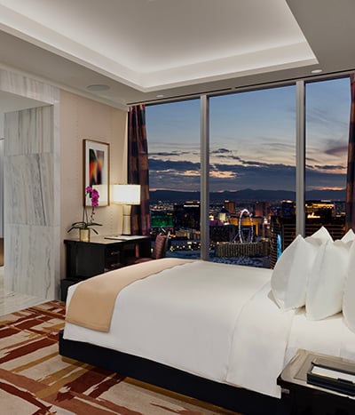 Bed framed by nightstands with a view of Las Vegas Strip in one of the rooms at Fontainebleau Las Vegas